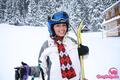 Ski girl outdoors holding skiis wearing helmet